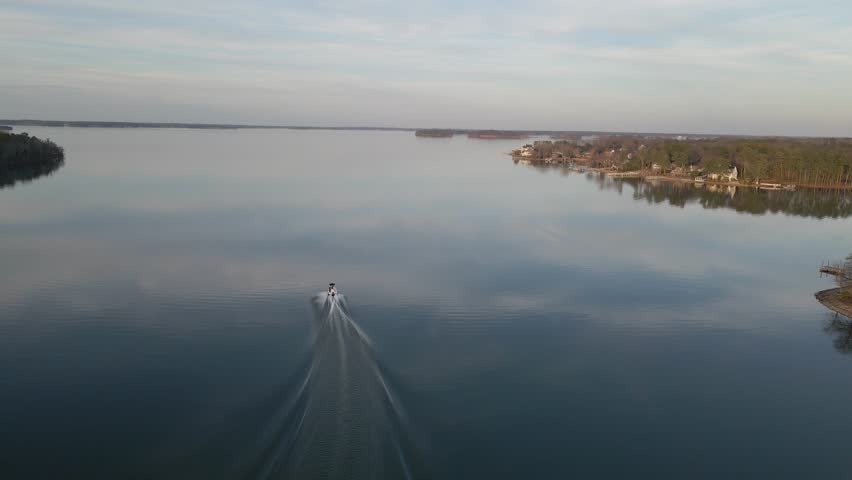Wide shot of a boat cruising on the lake in the evening. Lake Murray in South Carolina.