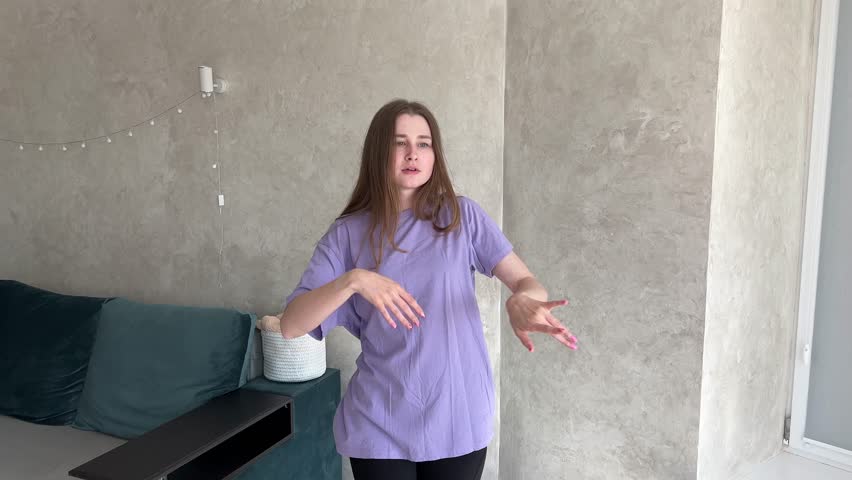 Young woman energetically dances in a modern living room, expressing passion with stylish decor and cozy interior