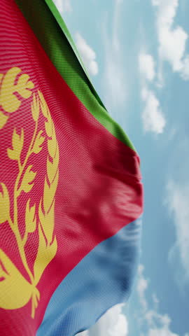 Wavy flag of Eritrea blowing in the wind in slow motion. Waving colorful Eritrean flag team symbol abstract vertical background. Blue sky with clouds. World countries flying flags concept