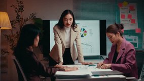 Businesswoman standing and gesturing while explaining a project to two colleagues during a night meeting in the office, fostering teamwork and collaboration through discussion and analysis - Powered by Shutterstock - Get 15% off with code: PIKWIZARD15