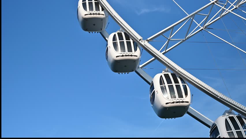 The attraction wheel rotates in the photo of the blue sky. An entertaining carousel on a hot summer day. Amusement park , spinning wheel on a blue sky background