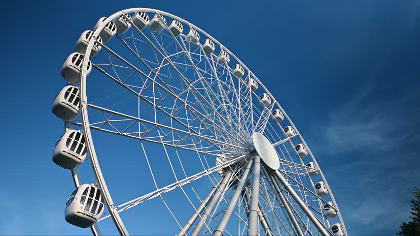 The attraction wheel rotates in the photo of the blue sky. An entertaining carousel on a hot summer day. Amusement park , spinning wheel on a blue sky background