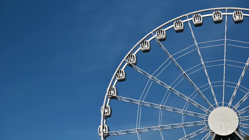 The attraction wheel rotates in the photo of the blue sky. An entertaining carousel on a hot summer day. Amusement park , spinning wheel on a blue sky background