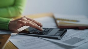 Accountant fingers pushing calculator buttons at cabinet table full of documents closeup. Unknown woman typing counting machine working alone. Entrepreneur hands calculating budget. Business concept  - Powered by Shutterstock - Get 15% off with code: PIKWIZARD15