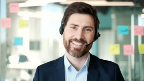 Webcam view. Confident businessman wearing headset communicating in modern office looking at camera. Professional male engaged in virtual meeting, showcasing effective communication skills. Close up  - Powered by Shutterstock - Get 15% off with code: PIKWIZARD15