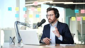 Confident tutor in wireless headphones giving video call training using microphone and laptop in business office. Businessman recording podcast. Blogger is streaming. Coach has an online course - Powered by Shutterstock - Get 15% off with code: PIKWIZARD15