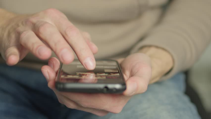 CloseUp of Hands Using Smartphone for Browsing and Communication. Person interacts with a mobile device, touching the screen, texting, and scrolling. Modern technology and connectivity