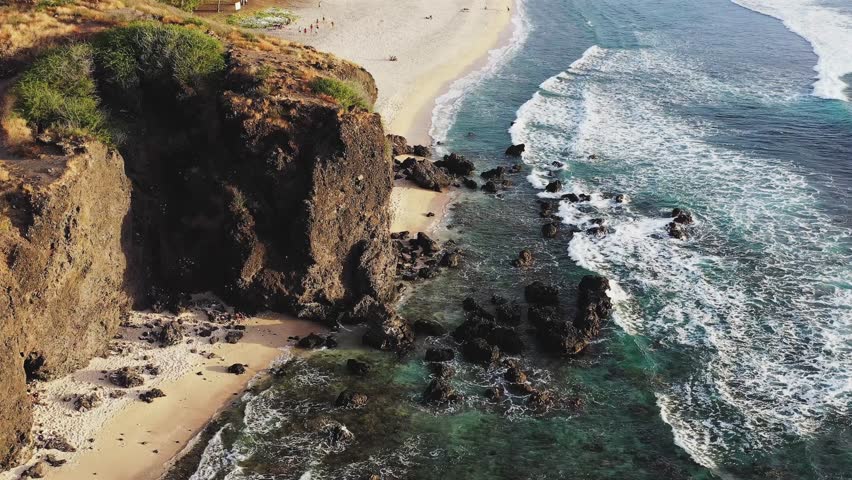 Aerial view of Plage des Aigrettes with golden hour waves, palm trees, and houses, Saint-Gilles-Les-Bains, Reunion.