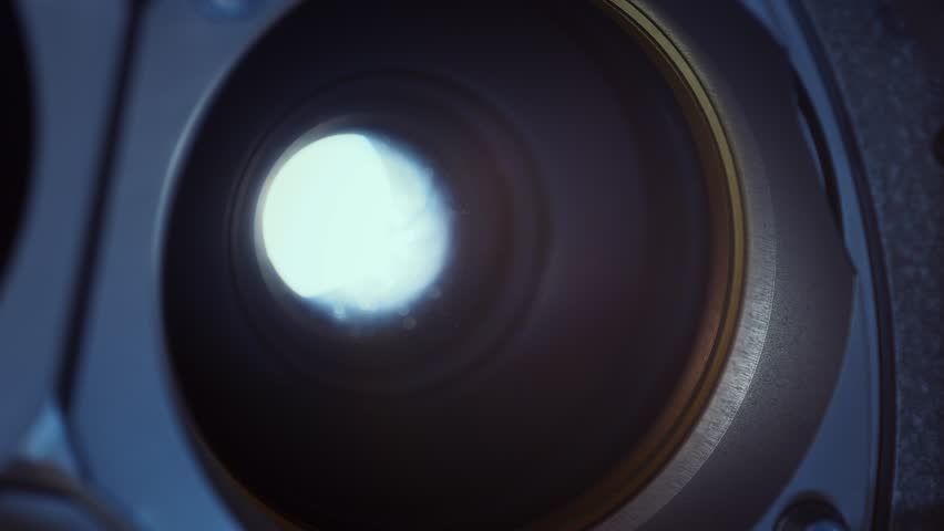 Lens of a flickering 35mm Cinema Projector in a movie theater during a performance- Classic film projector in a cinema. Close-up shot