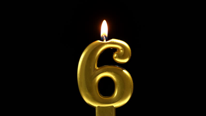 Golden number 6 birthday candle burning against a black background, creating a sleek and elegant celebration scene.