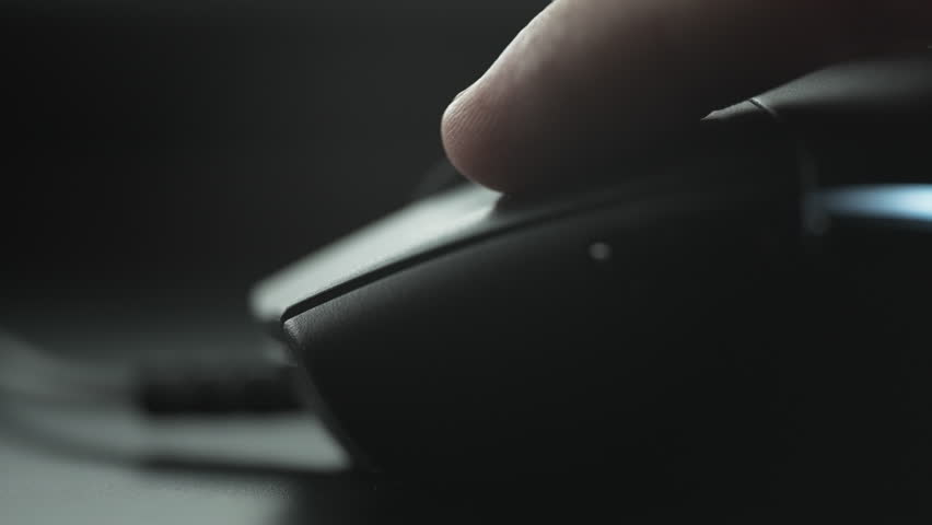 Clicking black computer mouse on a work desk. Close up.