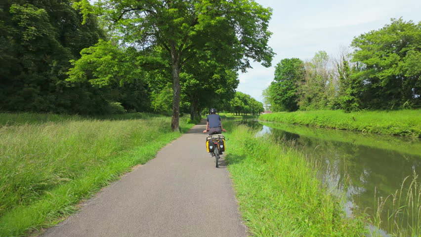 Teen Riding Bike along French Canal in Spring