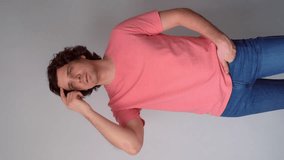 Pensive thoughtful curly dreaming friendly man looking up on gray background. Guy model wearing pink t-shirt, jeans posing working in studio. Portrait of optimistic caucasian male, vertical video. - Powered by Shutterstock - Get 15% off with code: PIKWIZARD15