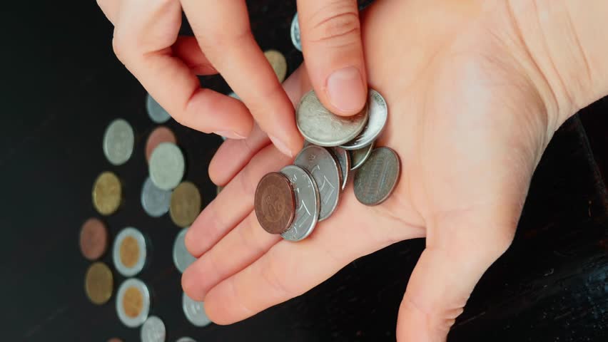 Person counting money coins against coins background, close up of hands. Female counts old antique coins in hands. Vertical video