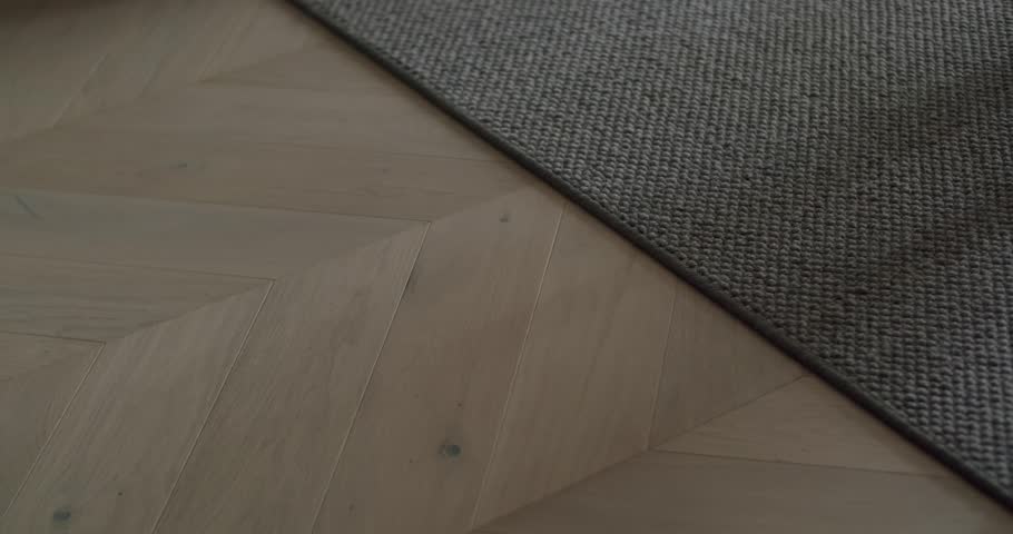 Close-up of a woman walking barefoot on a wooden floor and carpet, highlighting comfort, warmth, and domestic lifestyle. Woman Walking Barefoot on Wooden Floor and Carpet in Cozy Home