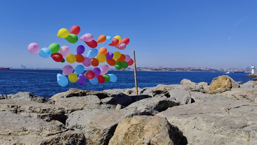 Colorful balloons on a string. The balloons are fluttering in the wind against the backdrop of the blue sea. Strong winds sway the balloons against the backdrop of the Bosphorus Strait. A child's game
