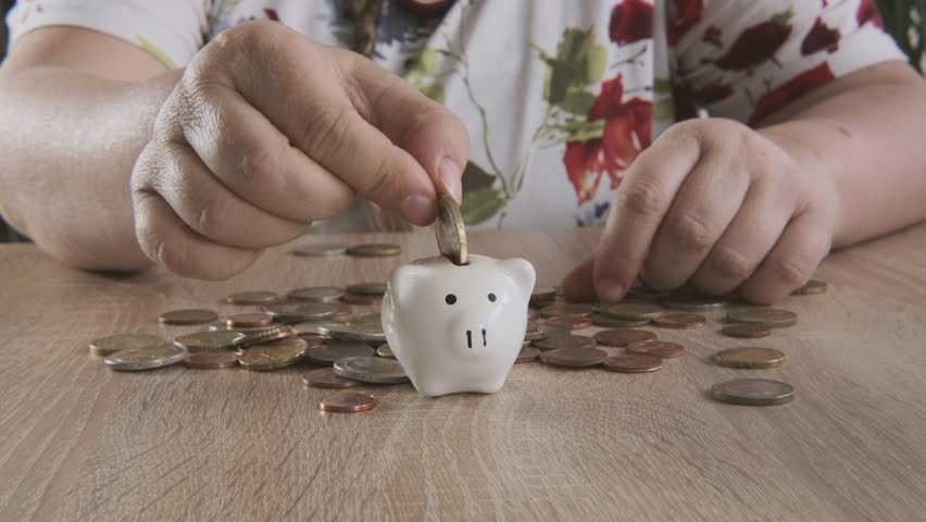 Mature woman counts wealth euro coins and placing into white piggy bank, financial responsibility and saving habits, joy of saving, satisfaction financial goals, life insurance