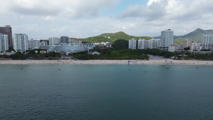 Aerial photography of the scenery around Dadonghai Bay in Sanya City, Hainan Province, China, and water entertainment activities such as motorboats and sailboats on the sea.