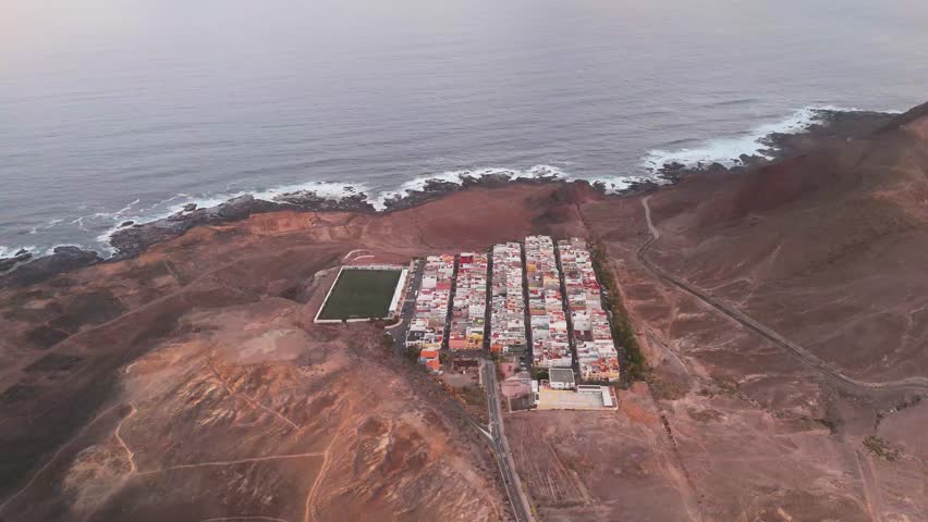 Aerial view of Las Coloradas Stadium surrounded by beautiful ocean and rugged coastline at sunset, Las Palmas de Gran Canaria, Spain.