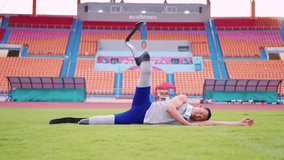 Asian para-athlete with prosthetic blades stretching leg in stadium. Attractive amputee sportsman runner lying down on the glass, warm up before practicing workout for Paralympics running competition. - Powered by Shutterstock - Get 15% off with code: PIKWIZARD15