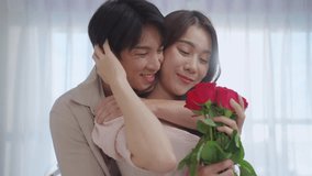 Asian young man surprise and give rose flower to beautiful girlfriend. Attractive romantic new marriage couple male and woman spend time to celebrate anniversary and valentine's day together in house. - Powered by Shutterstock - Get 15% off with code: PIKWIZARD15