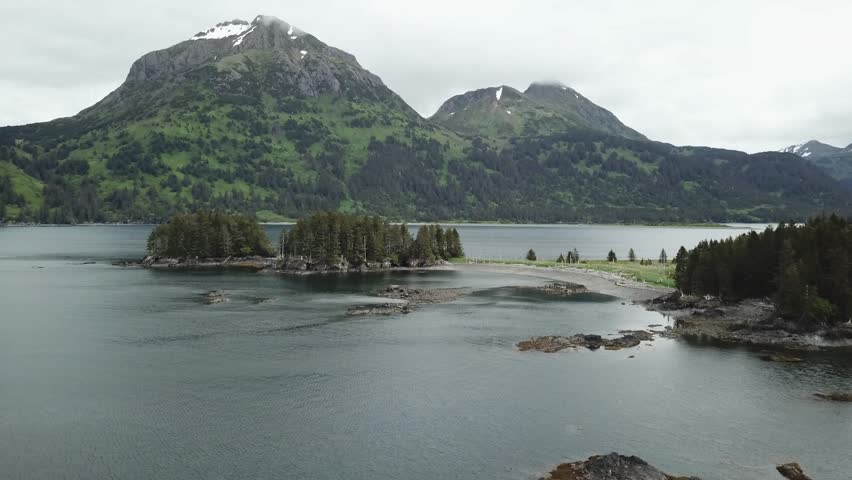Aerial drone video of Port Chatham bay and Portlock, Alaska with mountains in the background with snow capped peaks.  
