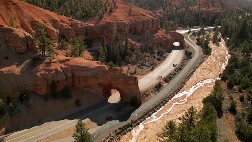 Aerial view of majestic red canyon with winding road and lush trees, Bryce Canyon City, United States.