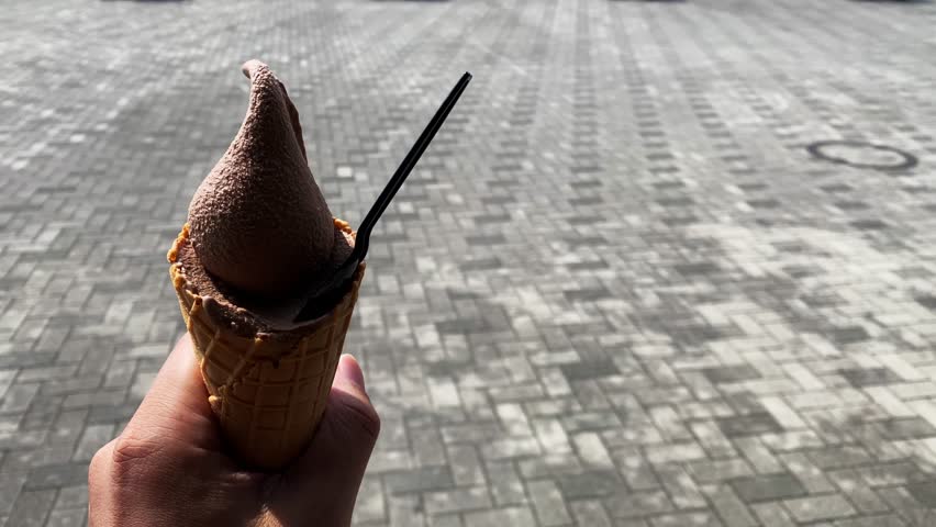 A chocolate flavor soft cream with left hand daytime close up handheld shot