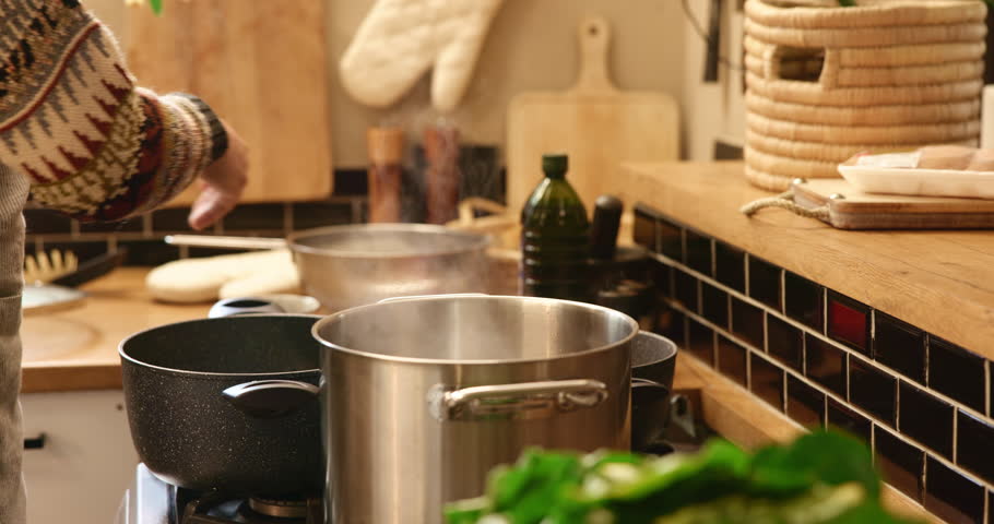 Hands, pot and salt in house for cooking, flavor and dinner with meal prep, brunch or stove in kitchen. Person, oven and spices in home for food, recipe or ingredients with diet, nutrition and steam