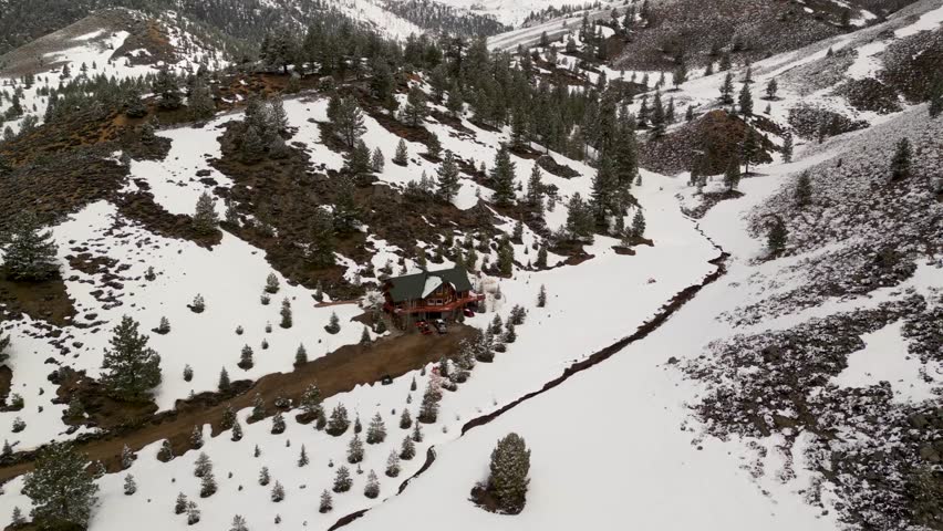 Aerial view of serene snowy landscape with a cabin surrounded by pine trees and mountains, Mono Lake Vista Point, Conway Summit, California, United States.