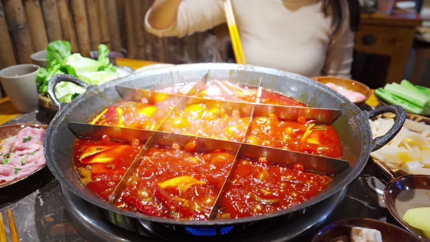 Female tourist eating original mala spicy hot pot in Chongqing, China