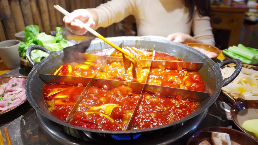 Female tourist eating original mala spicy hot pot in Chongqing, China