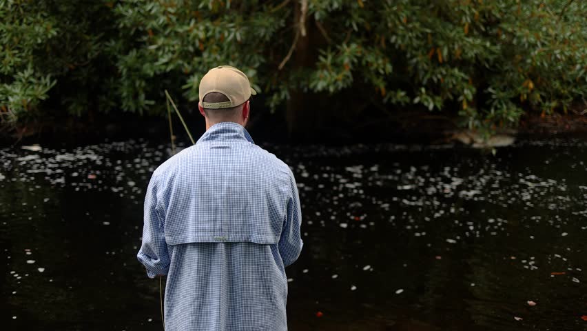 Slow Motion over-the-shoulder POV footage of a Fly Fisherman in the Pocono Mountains in Pennsylvania casting into the stream. The angler is fishing for Brook Trout, Rainbow Trout, or Brown Trout.