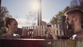 Romantic couple relaxing and enjoying the soothing warm waters of an outdoor hot tub, toasting and drinking red wine, handheld shot. - Powered by Shutterstock - Get 15% off with code: PIKWIZARD15