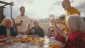 Cinematic footage of a group of seniors eating on a rooftop terrace of a beautiful house. Old friends reunited, having fun remembering stories and sharing good food. Concept about seniority. - Powered by Shutterstock - Get 15% off with code: PIKWIZARD15