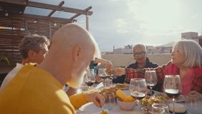 Cinematic footage of a group of seniors eating on a rooftop terrace of a beautiful house. Old friends reunited, having fun remembering stories and sharing good food. Concept about seniority. - Powered by Shutterstock - Get 15% off with code: PIKWIZARD15