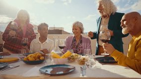 Cinematic footage of a group of seniors eating on a rooftop terrace of a beautiful house. Old friends reunited, having fun remembering stories and sharing good food. Concept about seniority. - Powered by Shutterstock - Get 15% off with code: PIKWIZARD15