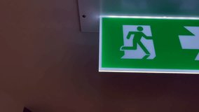 an illuminated emergency exit sign with a green background, featuring a person running towards the right arrow, Ideal for safety, emergency preparedness, architectural content - Powered by Shutterstock - Get 15% off with code: PIKWIZARD15