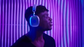 Dancing clubbing cyber space African American man in headphones listening music audio sound quality in neon innovation violet blue futuristic studio club futurism guy male dance enjoying song moving - Powered by Shutterstock - Get 15% off with code: PIKWIZARD15