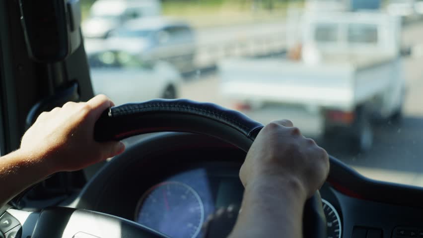 Hands of a Truck Driver in Action: Close-Up of Steering the Wheel During Long-Distance Cargo Transport and Road Traffic Navigation. High quality 4k footage