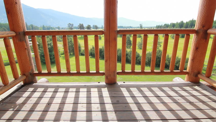 Log home balcony reveal green field with mountains and trees