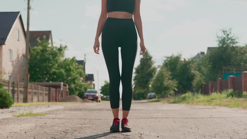 Female runner preparing at start point and start to run. Slim fitness runner in sportswear starts running
