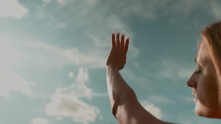 Silhouette of a happy dreaming girl pulls her hand to the sun. Religion helping hand. Prayer in religion. Silhouette of a hand in the sun sunset. Female looking at her proposal ring with diamond 