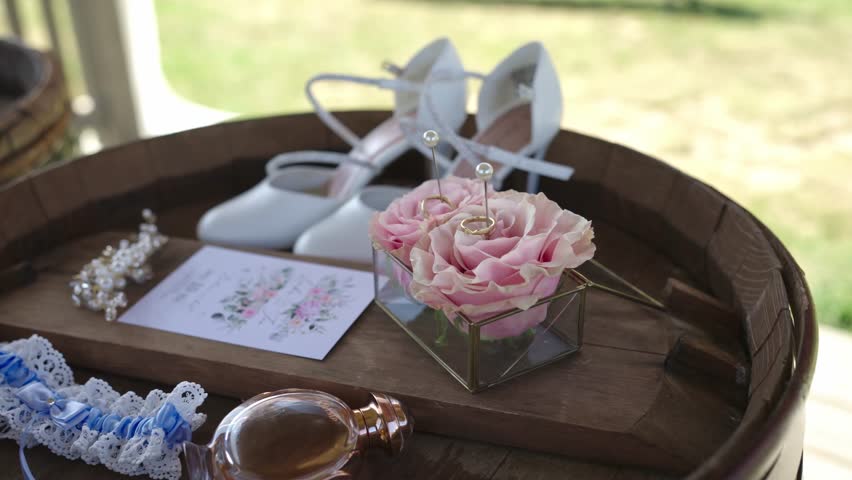 Wedding rings, the bride's shoes, a garter, and a wedding invitation arranged together for a stylish presentation of wedding items.