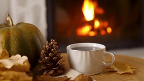 Cozy autumn. Cup of tea, pumpkin, autumn leaves on wooden table on background of warm fireplace. Fall in living room footage. Thanksgiving and Halloween. - Powered by Shutterstock - Get 15% off with code: PIKWIZARD15