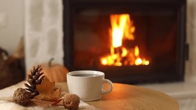 Autumn hygge. Cup of warm tea, pumpkins, autumn leaves on wooden table against burning fireplace in living room. Cozy fall footage. Thanksgiving and Halloween. - Powered by Shutterstock - Get 15% off with code: PIKWIZARD15