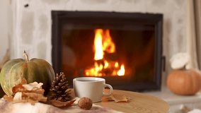 Autumn hygge. Cup of warm tea, pumpkins, autumn leaves on wooden table against burning fireplace in living room. Cozy fall footage. Thanksgiving and Halloween. - Powered by Shutterstock - Get 15% off with code: PIKWIZARD15