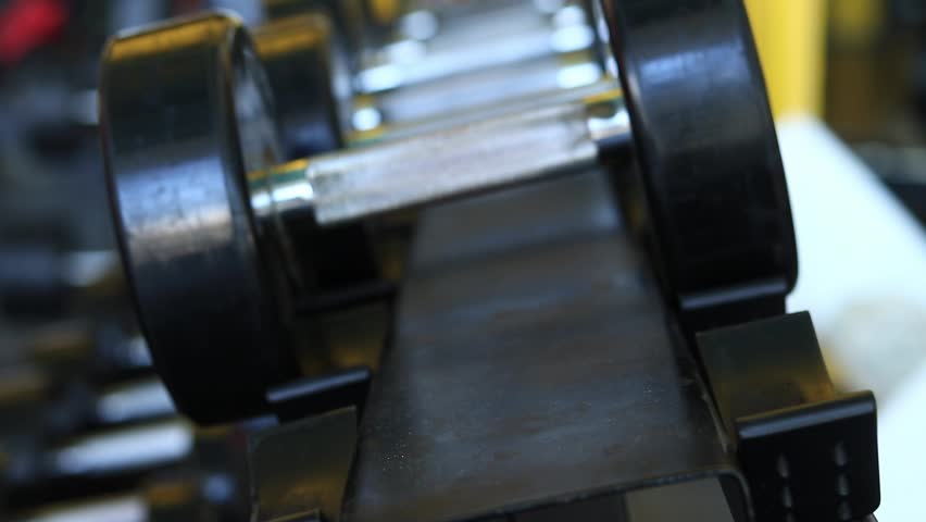 Female hands, bodybuilding. Dumbbells in the gym. Close-up of female hand placing dumbbell on the rack for training in the gym. Strength training with fitness equipment. Sports concept
