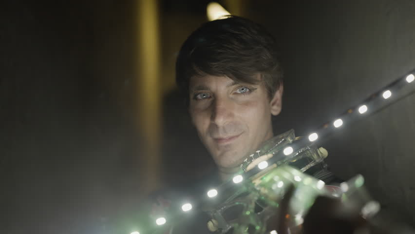 Man with intense gaze plays luminous violin at night
