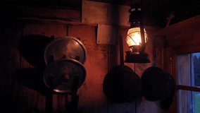 Kerosene lantern casts warm glow over a rustic kitchen, highlighting metal pots and lids hanging on the wooden wall. - Powered by Shutterstock - Get 15% off with code: PIKWIZARD15